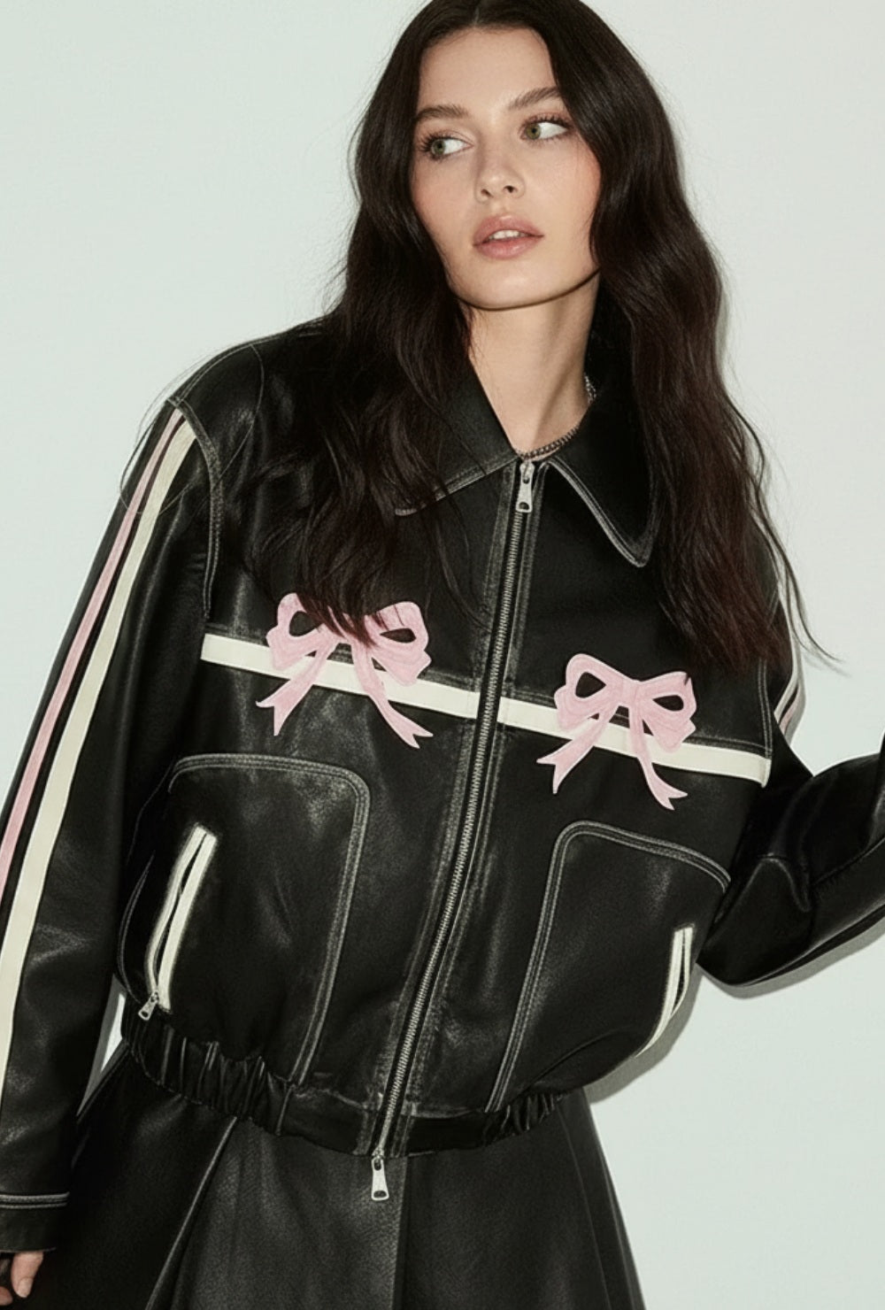 Czarna skórzana kurtka z zamkiem i dekoracyjnymi kokardkami na piersi