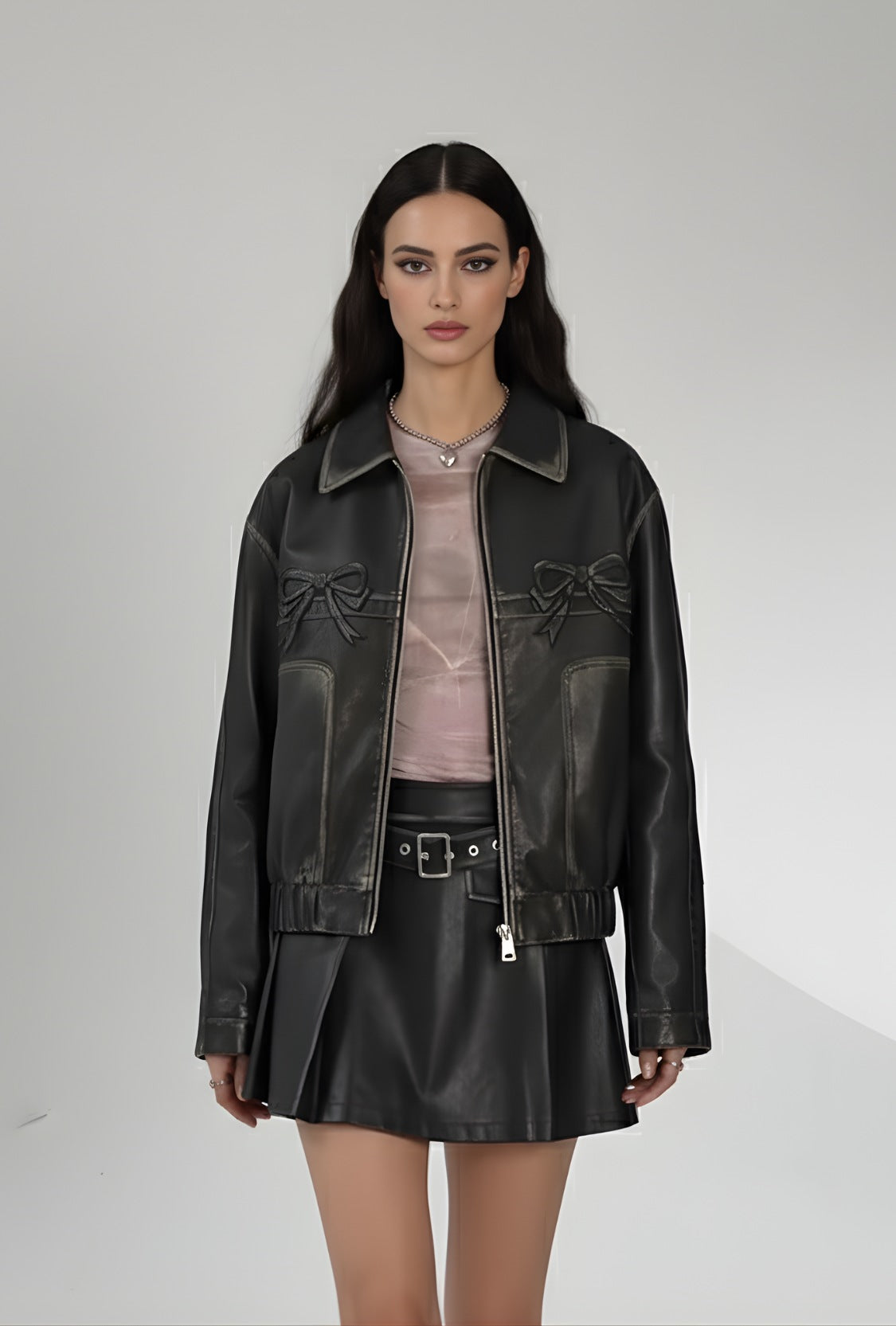 Czarna skórzana kurtka z zamkiem i dekoracyjnymi kokardkami na piersi