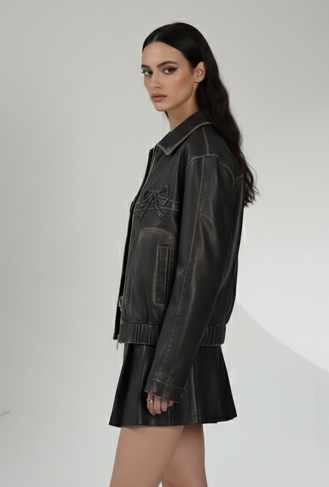 Czarna skórzana kurtka z zamkiem i dekoracyjnymi kokardkami na piersi