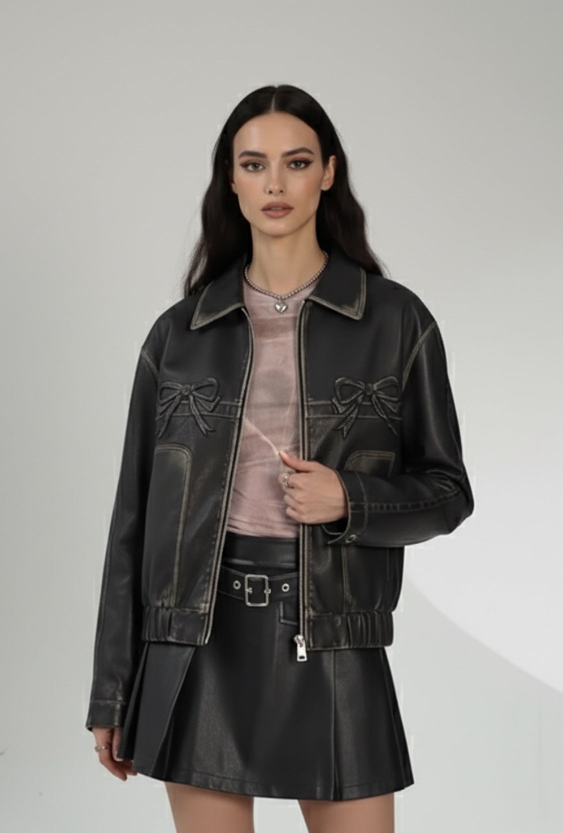 Czarna skórzana kurtka z zamkiem i dekoracyjnymi kokardkami na piersi