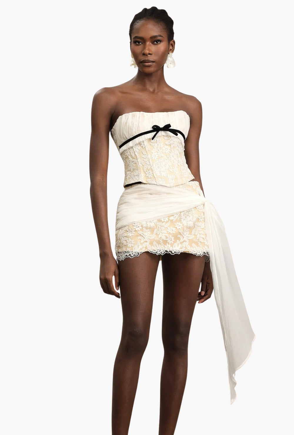 Koronkowy komplet kremowo-beżowy z gorsetem bez ramiączek, kokardką i mini spódniczką z marszczeniem oraz trenem